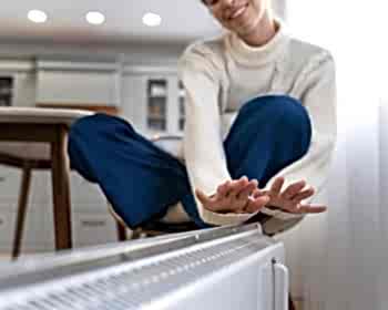 smiley-woman-sitting-near-heater-home_23-2149335095